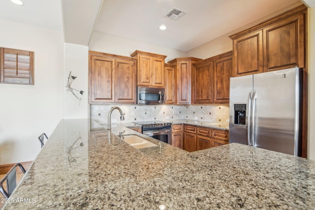 kitchen with stainless steel appliances, visible vents, a sink, and light stone countertops