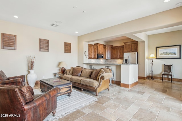 living area featuring baseboards, recessed lighting, visible vents, and stone tile floors