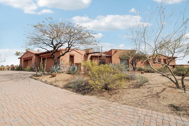 adobe home featuring a garage, decorative driveway, and stucco siding