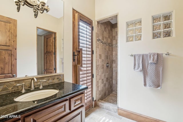 bathroom with a tile shower, a notable chandelier, and vanity