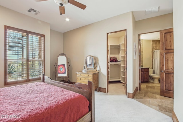 bedroom featuring stone finish flooring, visible vents, a spacious closet, and baseboards