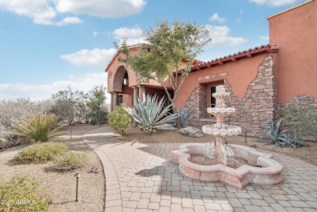 exterior space with stone siding, a tiled roof, and stucco siding