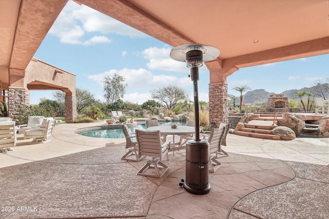 view of patio / terrace with outdoor dining area, a mountain view, and an outdoor pool