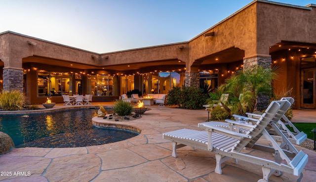 pool with an outdoor fire pit and a patio