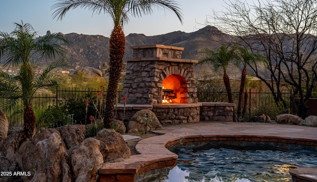 exterior space with fence, an outdoor stone fireplace, and a mountain view