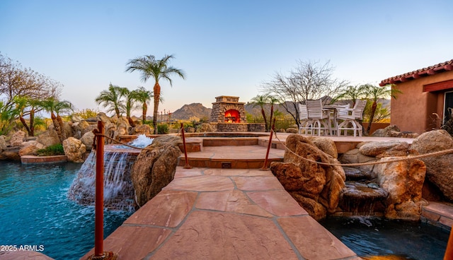 exterior space featuring an outdoor stone fireplace and a patio area