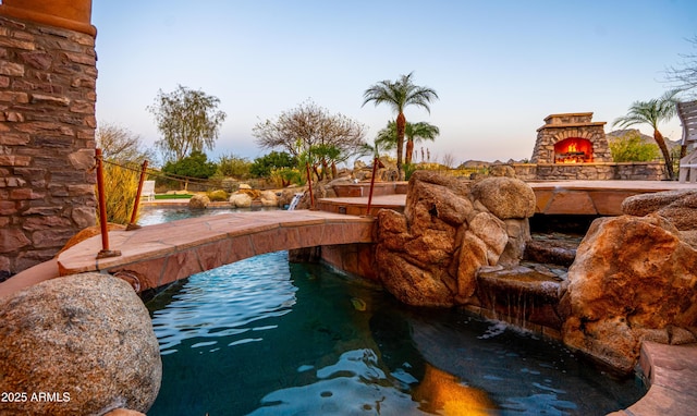 pool with an outdoor stone fireplace