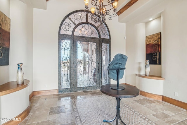 entrance foyer with a notable chandelier, baseboards, and stone tile flooring