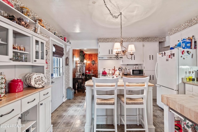 kitchen featuring pendant lighting, white refrigerator, white cabinetry, a chandelier, and tile flooring