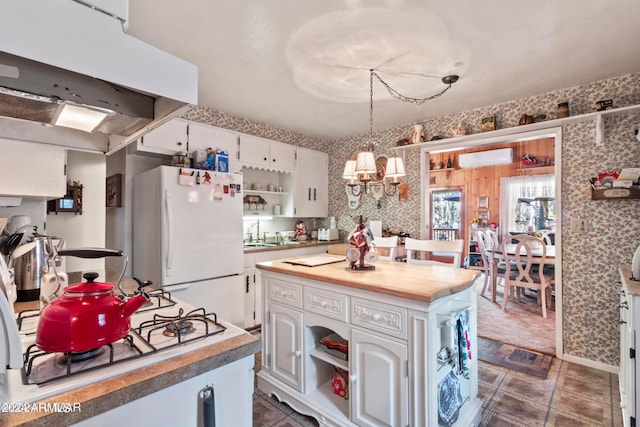 kitchen with dark tile floors, white refrigerator, white cabinetry, a kitchen island, and exhaust hood