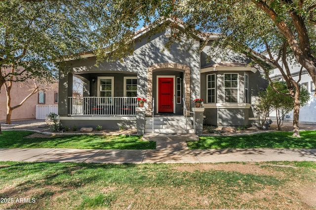 view of front of home featuring covered porch, a front yard, and stucco siding