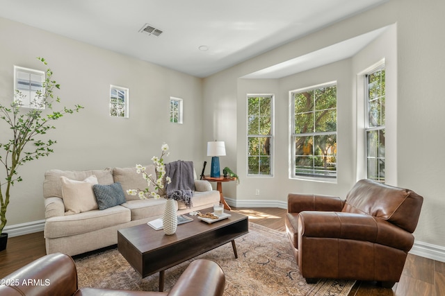 living area featuring visible vents, baseboards, and wood finished floors