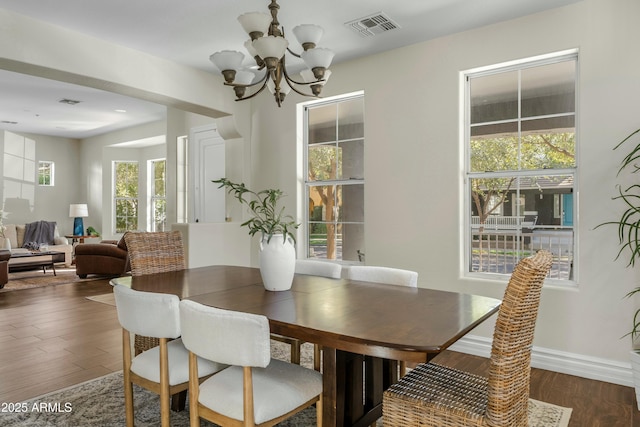 dining room featuring baseboards, wood finished floors, visible vents, and a notable chandelier