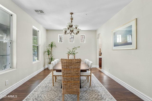 dining room featuring arched walkways, dark wood-style flooring, visible vents, and baseboards