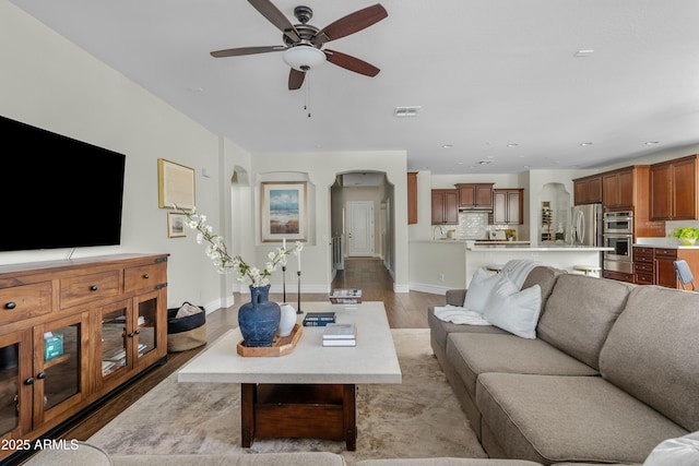 living area with arched walkways, recessed lighting, visible vents, a ceiling fan, and wood finished floors