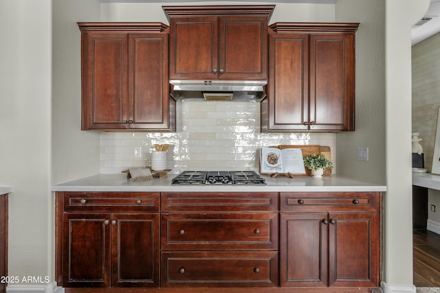 kitchen with tasteful backsplash, light countertops, visible vents, gas cooktop, and under cabinet range hood