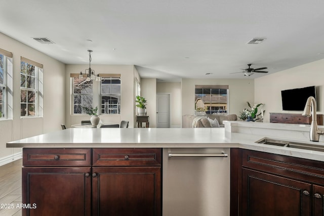 kitchen featuring open floor plan, dark brown cabinets, stainless steel dishwasher, and light countertops