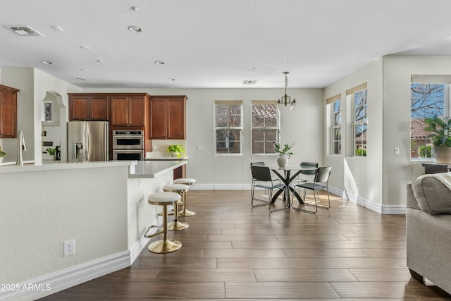 kitchen featuring light countertops, appliances with stainless steel finishes, dark wood-style flooring, and a breakfast bar