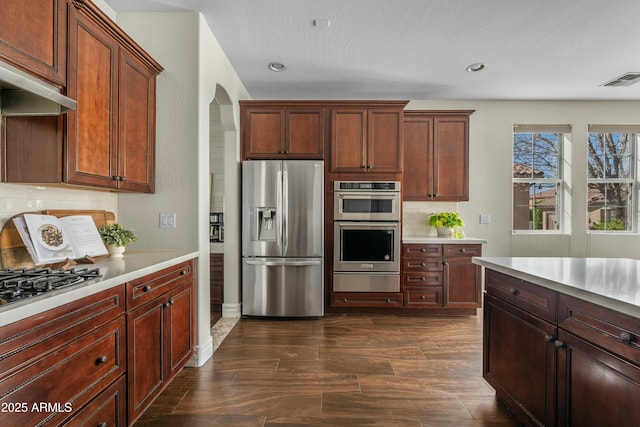 kitchen featuring visible vents, dark wood-style floors, stainless steel appliances, light countertops, and backsplash