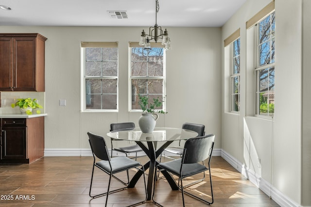 dining area with baseboards, visible vents, dark wood finished floors, and a chandelier