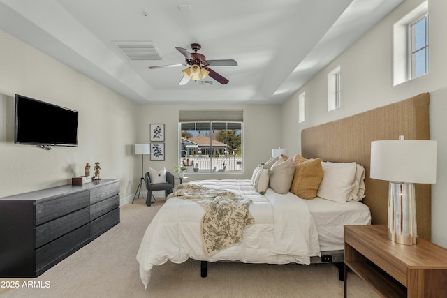 bedroom with baseboards, visible vents, ceiling fan, a tray ceiling, and carpet flooring