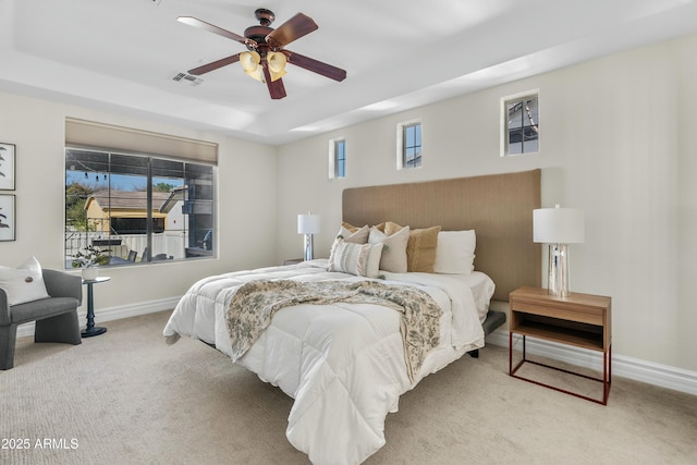 bedroom with a ceiling fan, visible vents, baseboards, a tray ceiling, and carpet