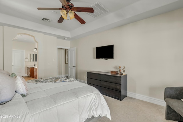 bedroom featuring arched walkways, a raised ceiling, visible vents, and baseboards