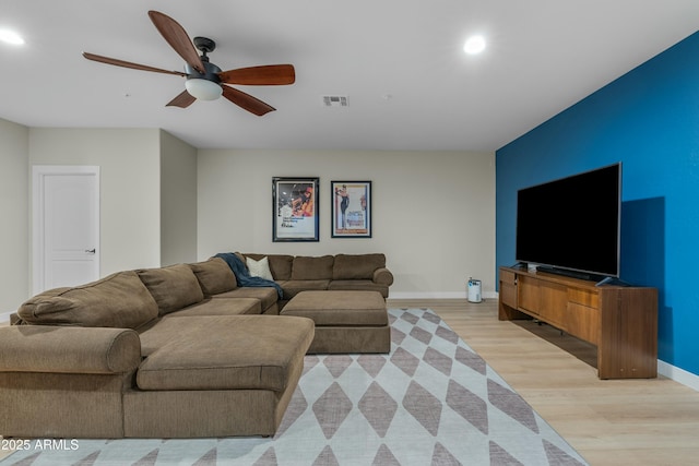 living area with light wood-style floors, visible vents, ceiling fan, and baseboards