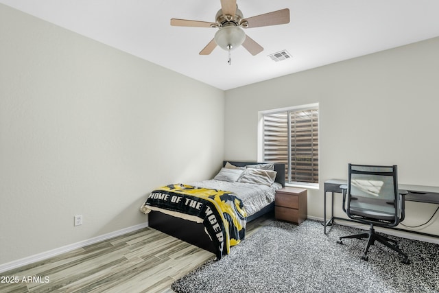 bedroom with ceiling fan, wood finished floors, visible vents, and baseboards