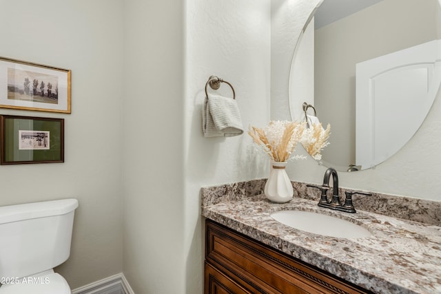 bathroom featuring baseboards, vanity, and toilet