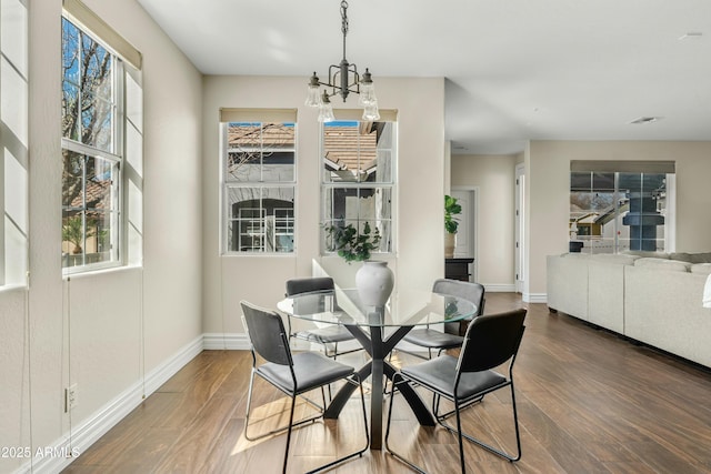 dining area with a chandelier, wood finished floors, visible vents, and baseboards