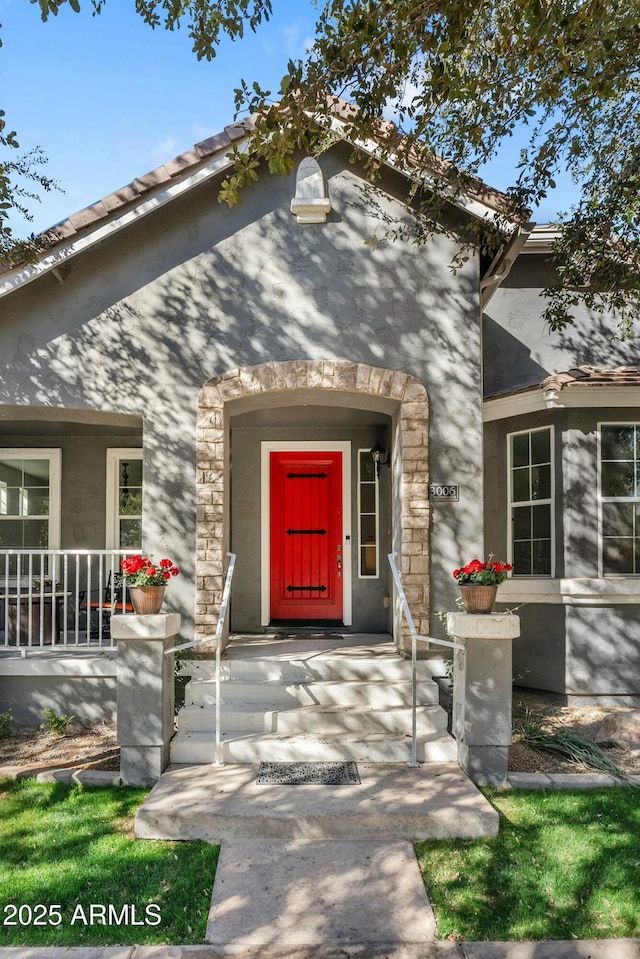 entrance to property with covered porch and stone siding