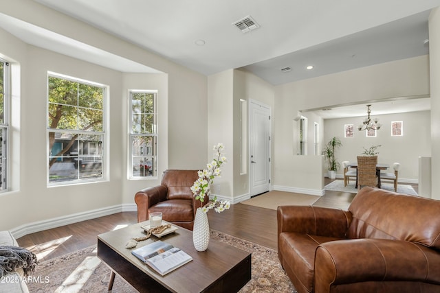 living area with a chandelier, light wood-style flooring, visible vents, and baseboards