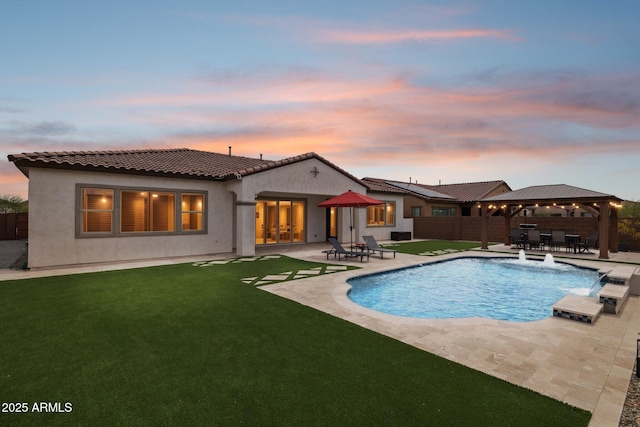 31490 N 126th Ln, Peoria, AZ 85383 - back of property at dusk with stucco siding, a patio area, a tiled roof, fence, and a lawn