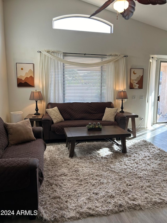 living room with a wealth of natural light, vaulted ceiling, ceiling fan, and hardwood / wood-style flooring