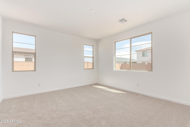 carpeted spare room featuring visible vents and baseboards