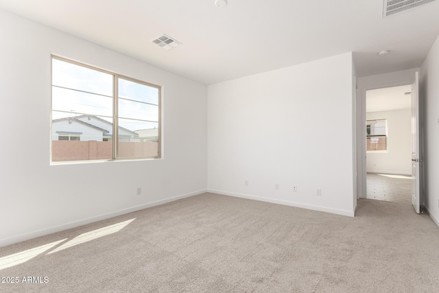 carpeted spare room featuring visible vents and baseboards