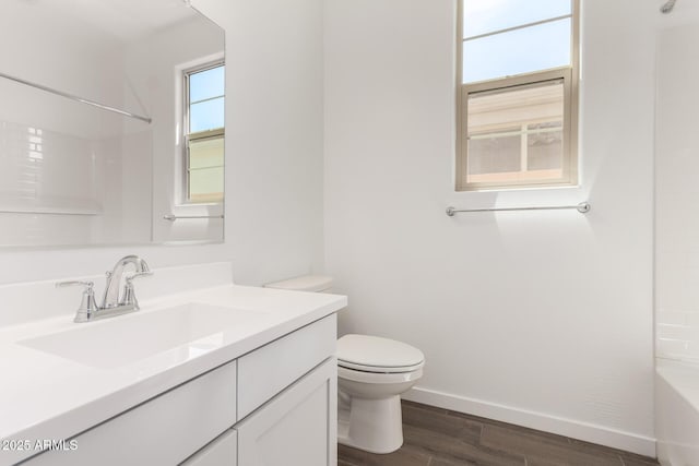 full bathroom with tub / shower combination, vanity, toilet, wood finished floors, and baseboards