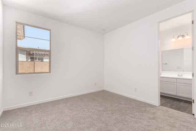 unfurnished bedroom with carpet flooring, baseboards, a sink, and connected bathroom