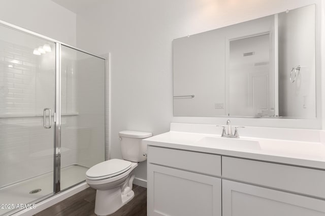 full bath featuring a shower stall, vanity, toilet, and wood finished floors