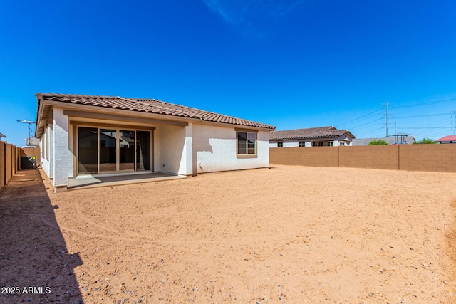 rear view of property featuring a fenced backyard, stucco siding, and a tile roof