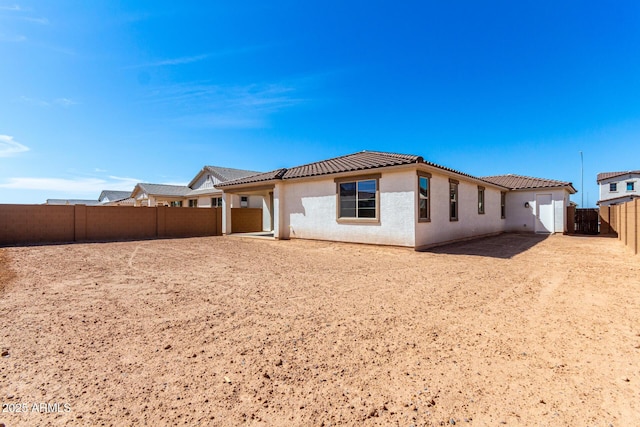 rear view of property featuring a fenced backyard, a tile roof, and stucco siding