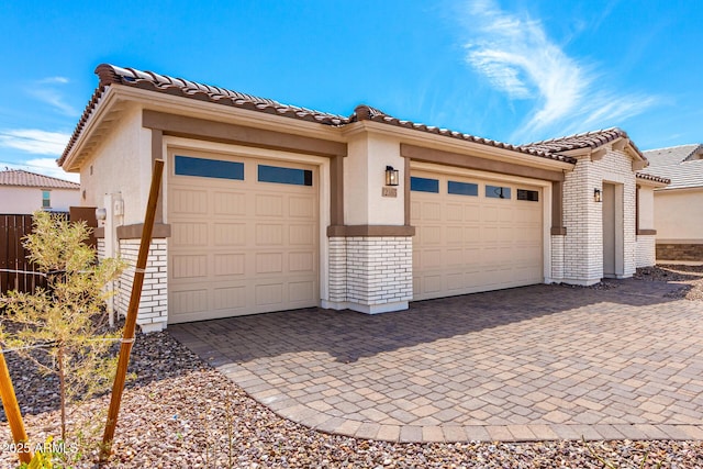 view of front of home featuring brick siding, fence, a garage, and stucco siding