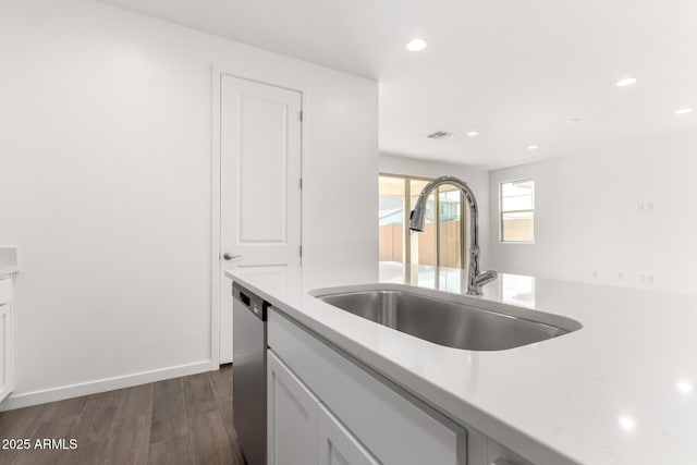 kitchen with white cabinets, dark wood-type flooring, dishwasher, and a sink