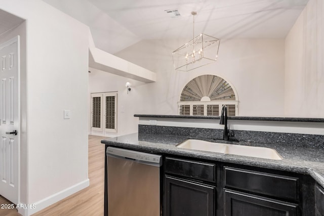 kitchen with stainless steel dishwasher, a sink, dark cabinetry, light wood-style flooring, and a chandelier
