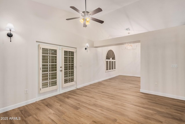 spare room with a chandelier, vaulted ceiling, wood finished floors, baseboards, and ceiling fan