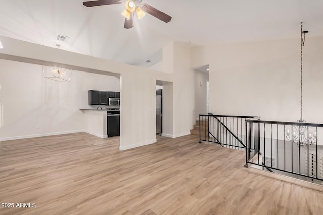 unfurnished living room featuring a chandelier, vaulted ceiling, light wood-style floors, and baseboards