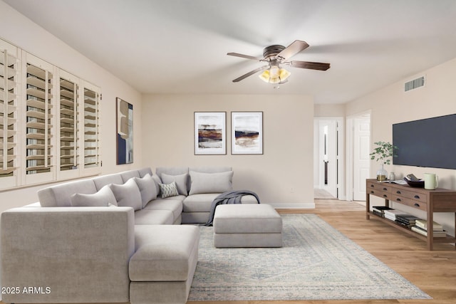 living room with wood finished floors, ceiling fan, and baseboards