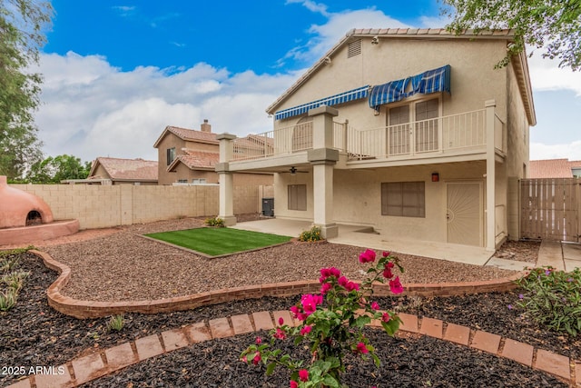 back of property with a balcony, stucco siding, and a patio area