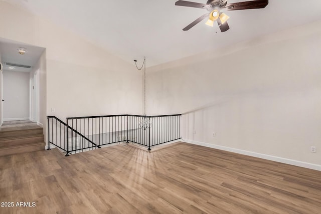 empty room with wood finished floors, baseboards, a ceiling fan, and lofted ceiling
